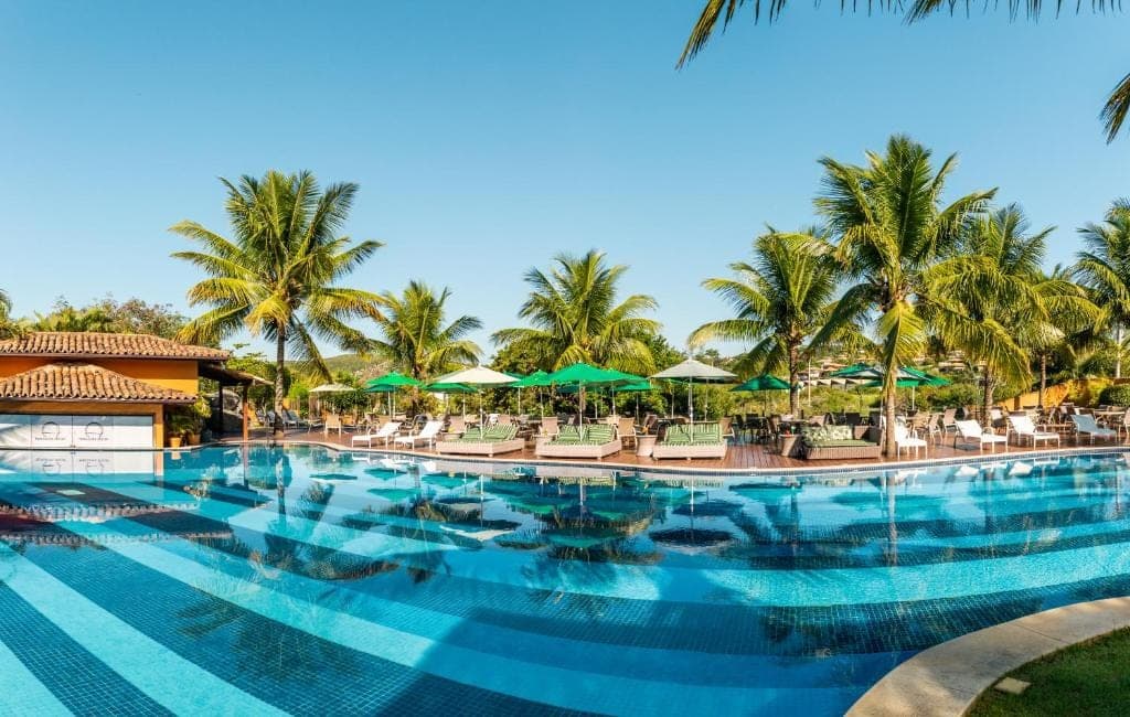 The resort pool surrounded by palm trees and sun loungers